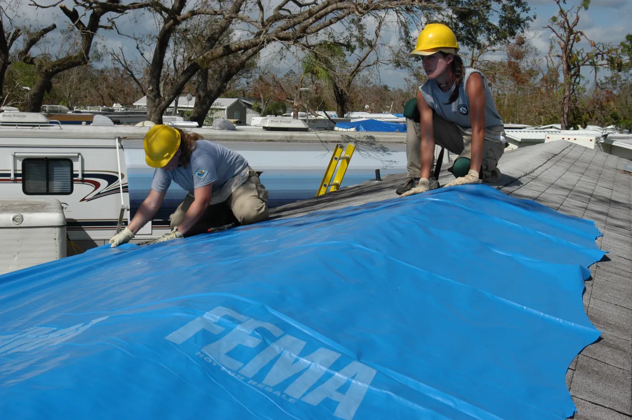 Image: Hurricane Charley - AmeriCorps members install FEMA blue plastic on a roof