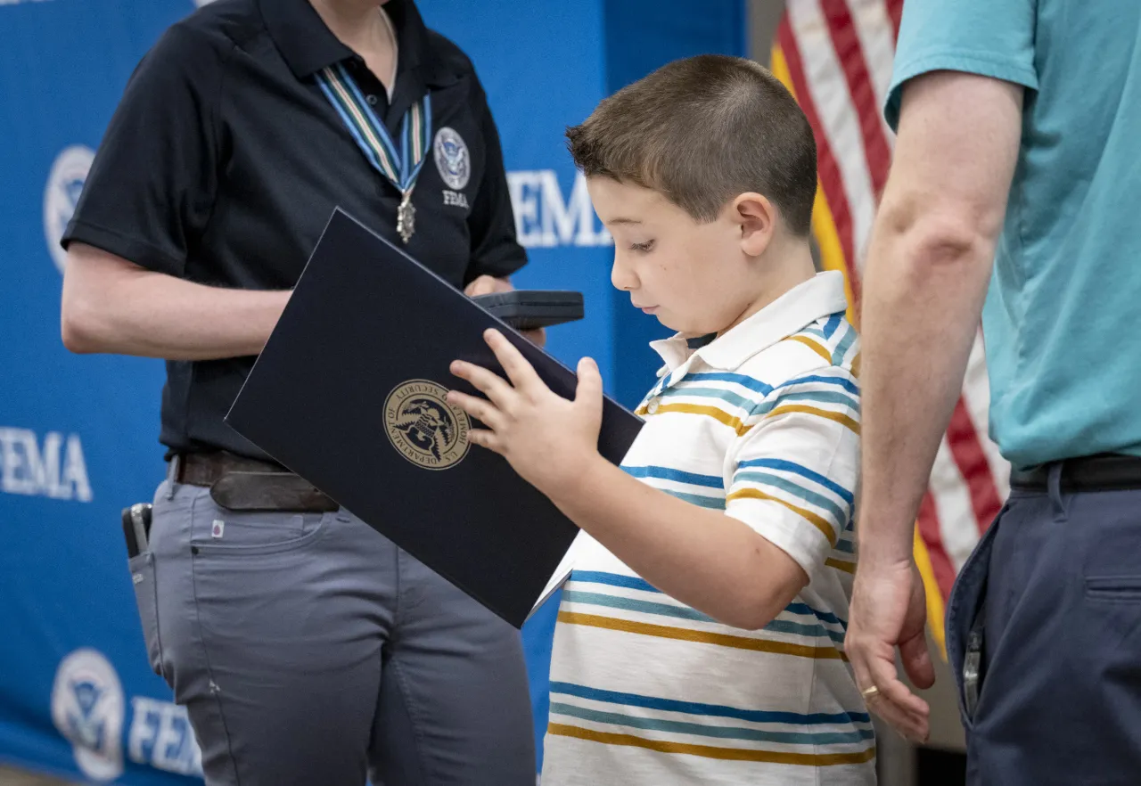 Image: Little Boy Reads Out of a DHS Portfolio