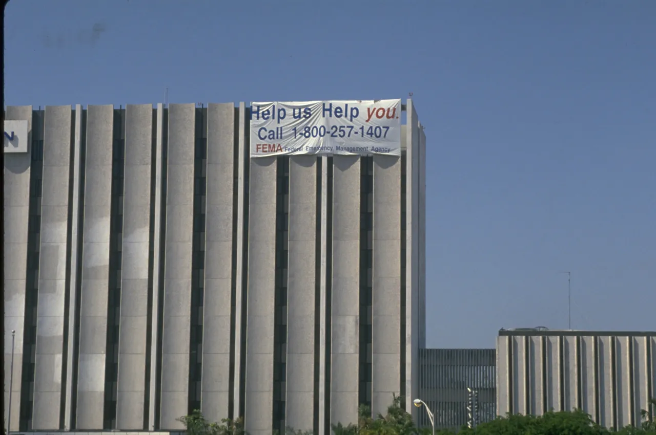 Image: Hurricane Andrew - A large sign on the side of building gives the FEMA hot line number