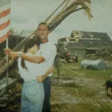 Image: Hurricane Andrew - Two survivors hug, holding the flag amongst rubble