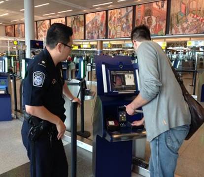 A police officer assisting a passengar at an airport self check-in.