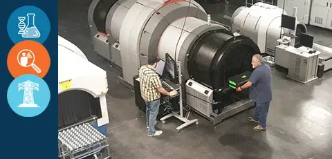 Two men working with big x-ray detecting machine.