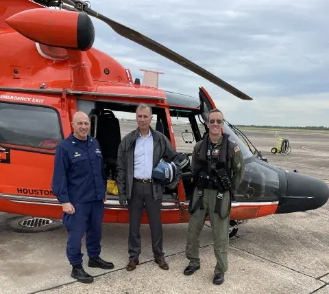 The Under Secretary Kusnezov standing in front of an USCG overflight helicopter with two other people.