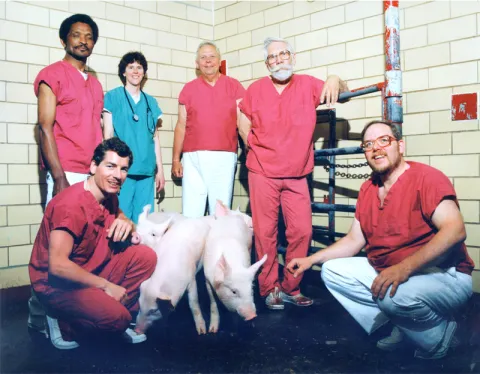 PIADC animal care staff in a room posing for a picture with two pigs.