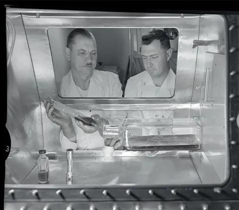 Two men using lab equipment in the PIADC microbiological investigations.