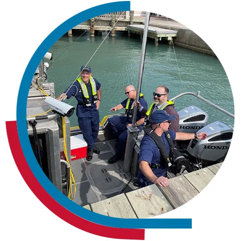 Four people in a U.S. Coast Guard boat in a body of water.