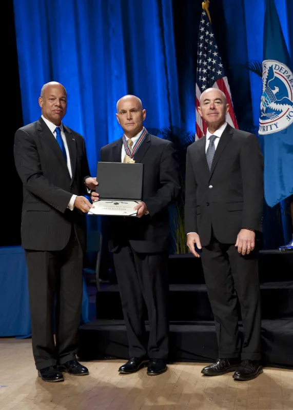 Secretary of Homeland Security Jeh Johnson and Deputy Secretary of Homeland Security Alejandro Mayorkas present the Secretary's Exceptional Service Gold Medal 2016 to Brett Gunter