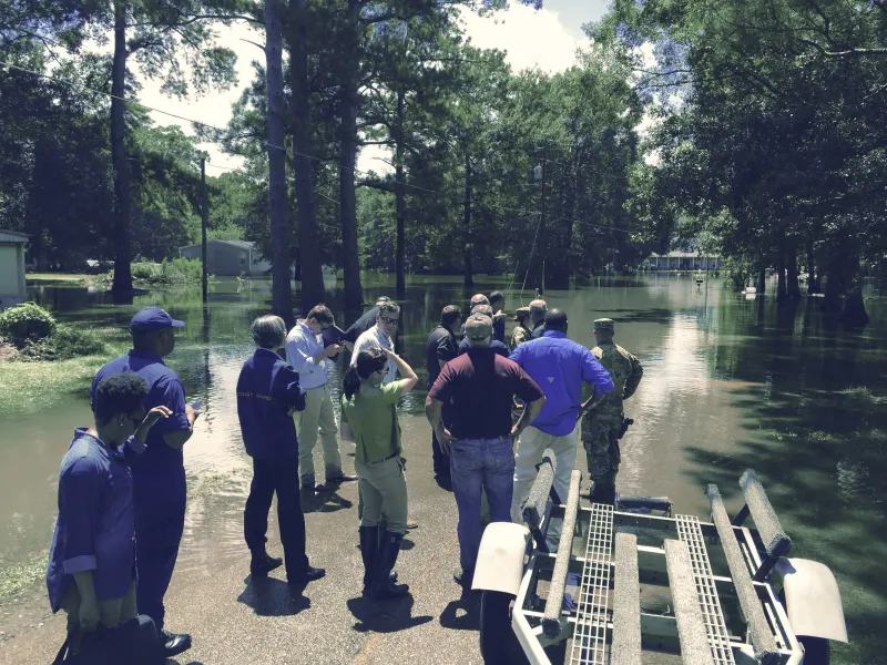 Secretary Johnson and members of walking tour stop and look out on submerged road