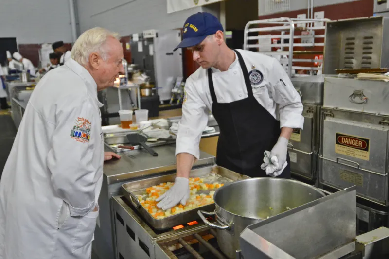 Petty Officer 2nd Class Ben Stockman chats with a judge during 42nd Annual Military Culinary Arts Competitive Training Event 