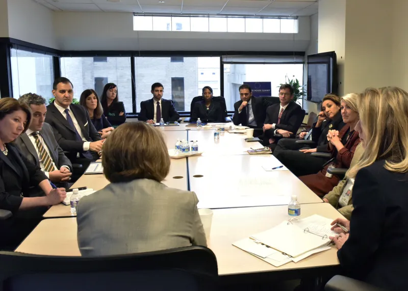 Lisa Monaco sits at the head of a conference table with many other people from the CVE Task Force.