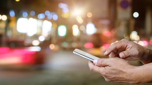 Hands using a smartphone on the busy street.