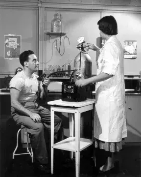 A white and black picture of a man and a woman in late 1940s in a laboratory