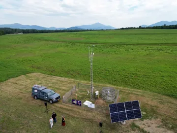 The EMPOWER network’s cutting-edge environmental and weather sensors set up on a green land with a pickup truck and several people nearby.