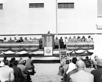 Former Secretary of Agriculture Ezra Taft Benson standing at a draped podium speaks before an audience at the dedication of the newly constructed Plum Island Animal Disease Laboratory in 1956.