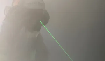 A fire fighter with a helmet on in a room full of smoke using the C-Thru technology.