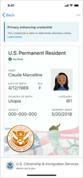 A digital mockup of a resident alien card issued by the U.S. Citizenship & Immigration Services. Top to bottom it reads, "Back" with a blue arrow. Below that it reads, " Privacy enhancing credential. This credential is able to selectively disclose claims. Learn more." Below that, it reads, "U.S. Permanent Resident", green check mark, "verified". Below that it reads, "Name Claudine Marcelline, Date of Birth, 4/12/1989, Sex F, Country of Birth, Utopia, Category IR1, USCIS#000-000-000, Resident since 5/20/2018." A background image of the U.S. flag and the Statue of Liberty and a seal reading "U.S. Department of Homeland Security", below that "U.S. Citizenship & Immigration Services demo.uscis.gov”.