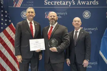 FLETC Director Benjamine Huffman (left), Innovation Award recipient Christopher McPipkin (center), with DHS Secretary Alejandro Mayorkas (right).