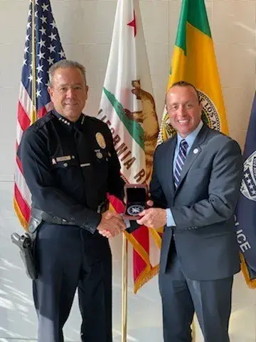 DHS Office of Intelligence & Analysis Under Secretary David J. Glawe (right) presents Los Angeles Police Department Chief Michael Moore (left) with the Office of Intelligence & Analysis medallion