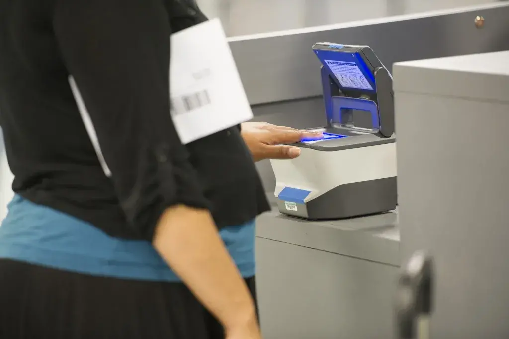 A woman allows a biometric device to scan her fingerprints.