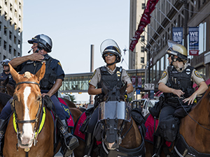 A photograph of horse-mounted police offiers supporting demonstrations during a national political convention.